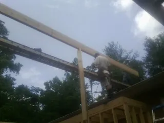 Carpenter setting a ridge beam over a new addition frame — Ice Dam Removal by Roofing Brothers in Hartstown