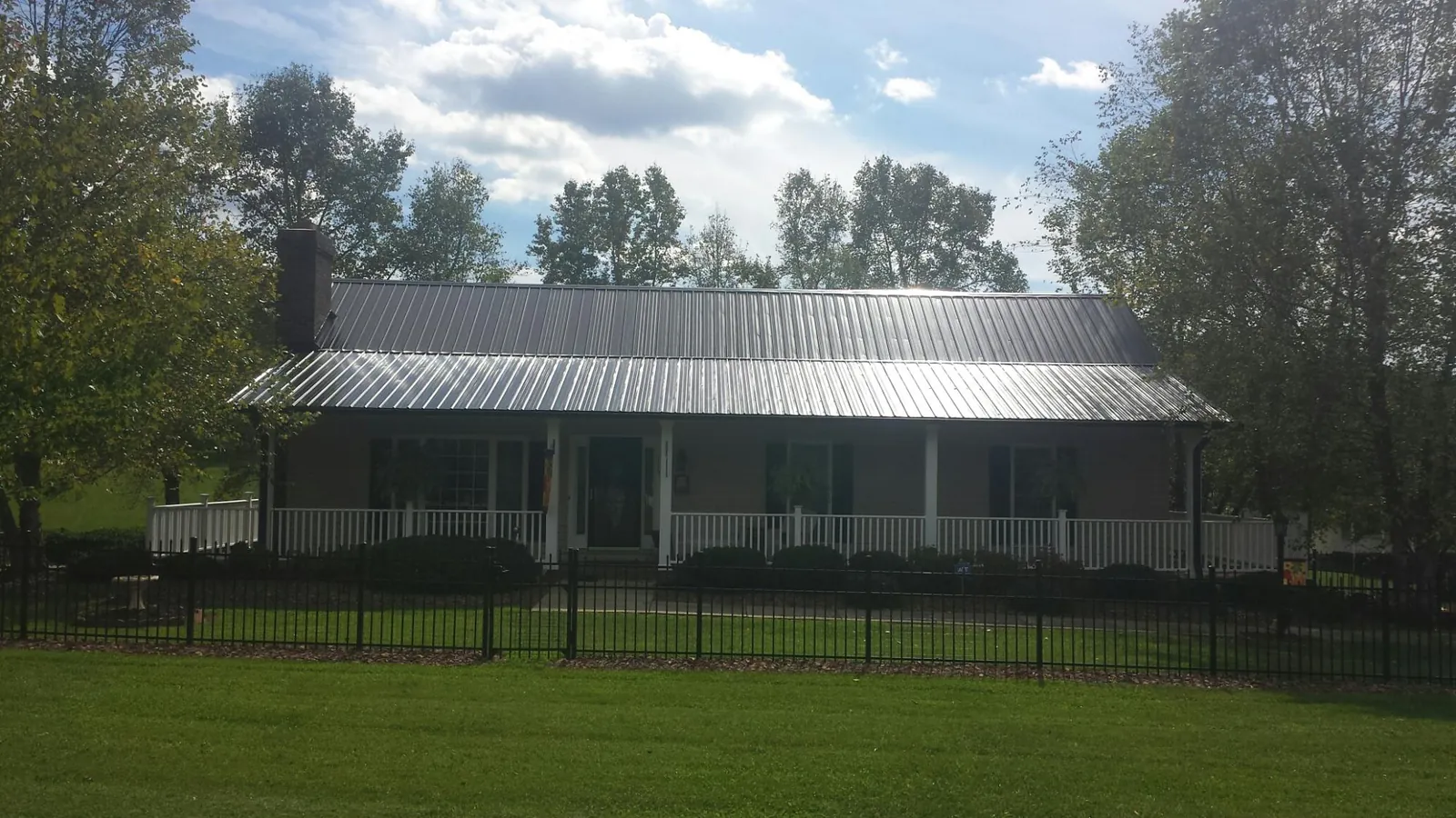Gray metal roof on a brick ranch with a full width front porch — Gutter Guard Installation work by our crew in Hartstown