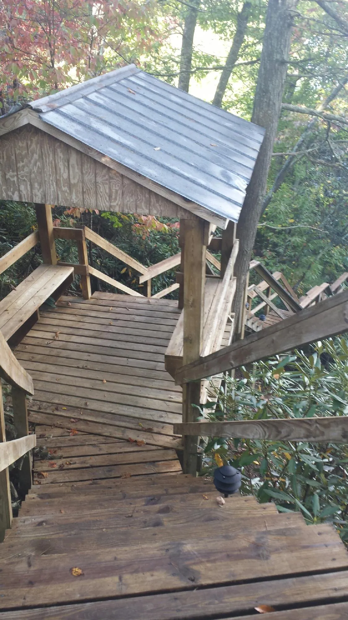 Metal roofed shelter over wooden steps on a wooded walkway — Skylight Repair & Installation work by our crew in Hartstown