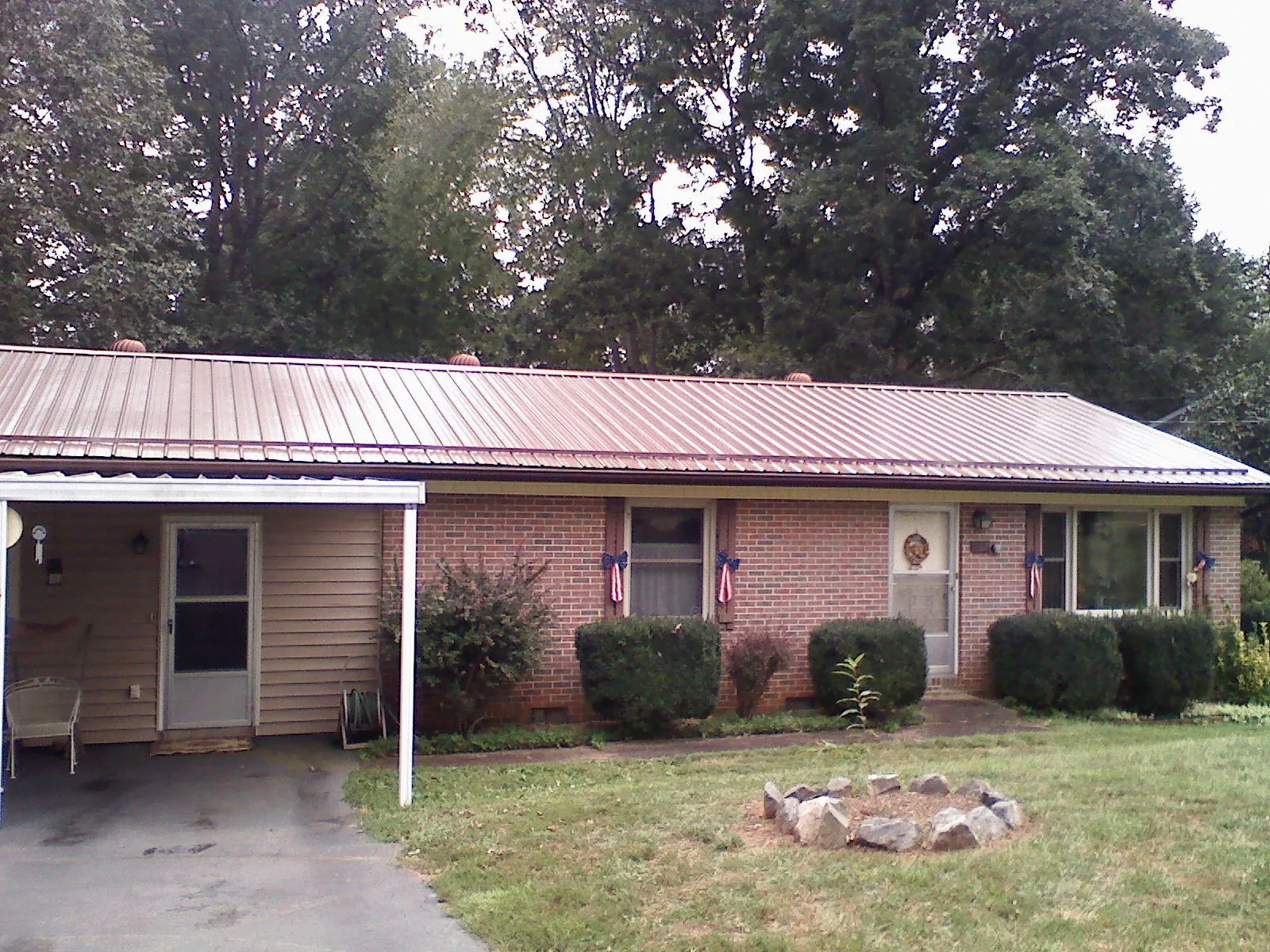 Bronze metal roof and carport on a brick ranch home — Roof Repair work by our crew in Hartstown