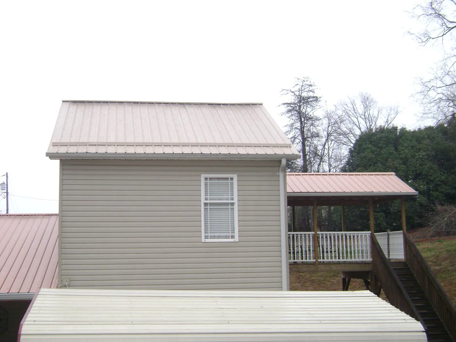 Tan metal roofs on a two story addition and attached porch, from a Roof Replacement job in Hartstown