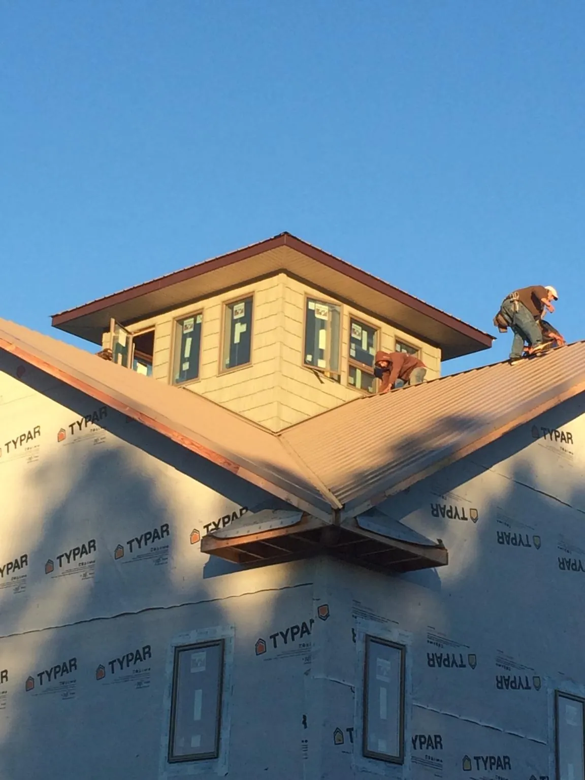 Roofers working around a rooftop cupola on a new metal roof at sunset — Roof Waterproofing in Hartstown by Roofing Brothers